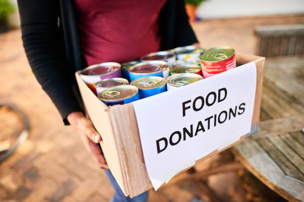 Close-up of a young woman standing outside with a box of food donations for a charitable cause