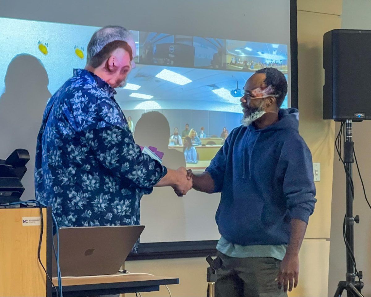 Philosophy professor and event organizer Daniel Jenkins, left, congratulates cybersecurity student Widmarck Francois, winner of the ethics essay contest, right, during the Oct. 24 Ethics and AI guest lecture event. Francois’ essay explored the personal stakes of AI accountability, resonating with the event’s focus on societal impact and ethical responsibility in technology.