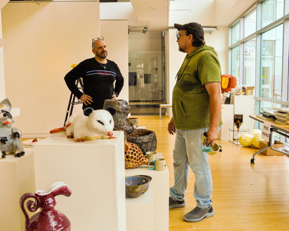 Pablo Callejo, instructional associate, left, and Michael Anthony, instructional coordinator, right, converse about an art matter on Sept. 14 in preparation for removing students’ fine art pieces from the King Street Gallery.