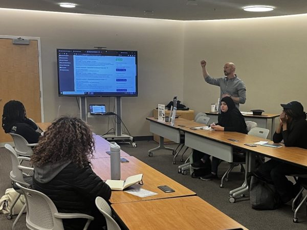 Justin R. Brown, student employment specialist, engages with attendees at Montgomery College’s LinkedIn workshop held on Nov. 14 at the Takoma Park/Silver Spring campus. He demonstrates how to identify and interact with job postings on LinkedIn, emphasizing the platform’s potential for career growth and networking.