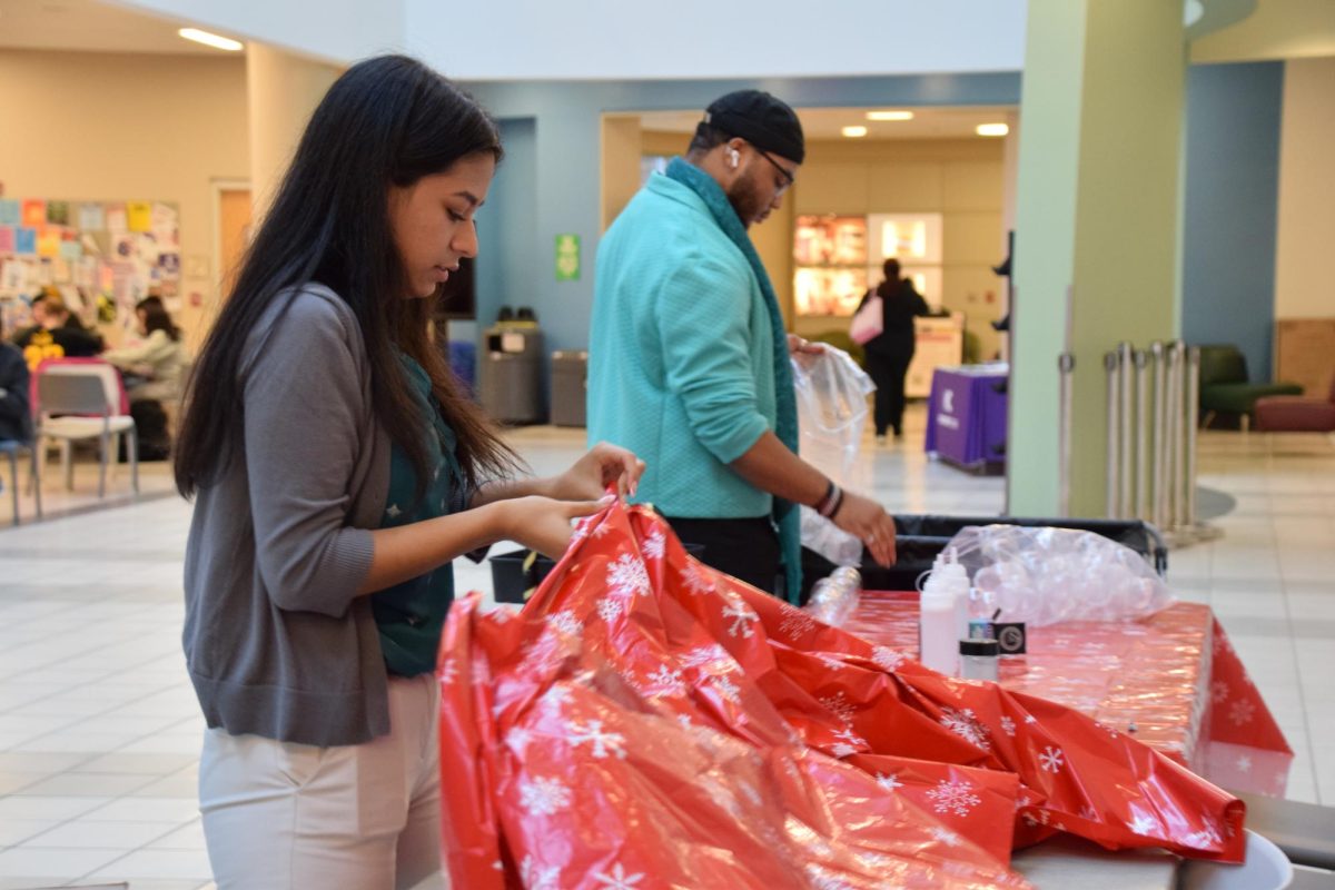 STEM major Sofia Perez and biological sciences major Eseme Matuke set up a table before the Holidays with SAB event on Dec. 11.